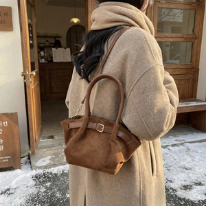 Winter faux suede handbag in dark brown, styled with a warm coat in a snowy cafe setting