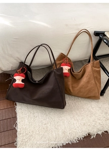 Dettaglio di borse tote in camoscio minimalista marrone e cammello con ciondoli mela