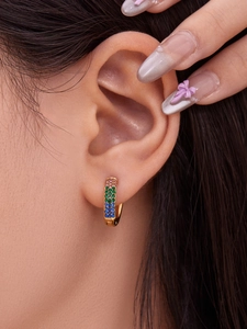 Detalle de pendientes en U dorados con circonitas de colores estilo arcoíris brillantes