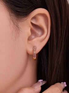 Primer plano de pendientes dorados en U con tres filas de circonitas rosa pavé