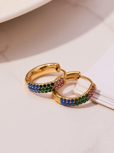 Detalle de pendientes de aro dorados en forma de U con tres filas de circonitas de colores