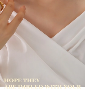 Close-up of gold chunky chain ring on finger with elegant white silk background