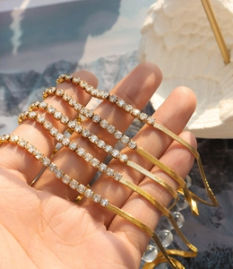 Close-up of gold herringbone chain and sparkling zircon tennis necklace set detail