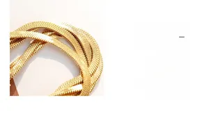 Detail of a gold plated flat snake chain necklace with a smooth polished metallic texture