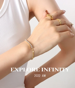 Detail of gold snake chain bracelet with sparkling zircon and minimalist rings set