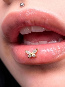 Close-up of golden butterfly labret stud with sparkling marquise and round crystals