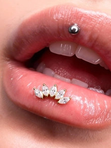 Close-up of titanium lip stud set with five marquise-cut zircons in a golden fan shape
