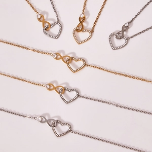 Collane con cuore e infinito in finitura oro e argento con zirconi su fondo beige