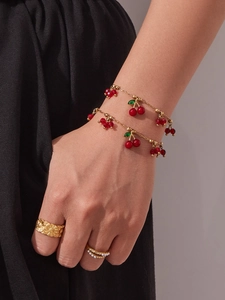 Dettaglio del bracciale con ciliegia placcato oro 18k e anello floreale su modella