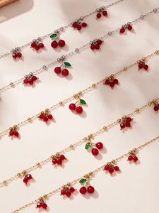 Dettaglio di collane con pendenti a ciliegia rossa su catene in oro e argento fini