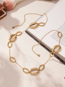 Nahaufnahme einer langen 18k vergoldeten geometrischen Halskette auf einem Buch mit Schatten