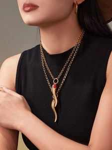 Macro detail of gold-plated cornicello chili pendants with red zircon accents on model