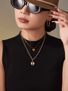 Détail de colliers superposés plaqués or avec pendentifs cœur et zircon sur un modèle