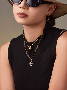Vue macro d'un collier double épaisseur doré avec pendentifs cœur et nez de cochon