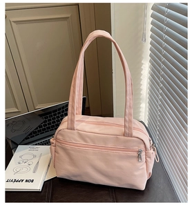 Detailed view of pink nylon tote bag showing zipper pockets and long shoulder handles