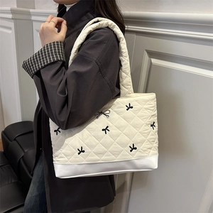 Borsa tote trapuntata color crema con ricamo a fiocco nero e tracolla larga