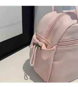 Close-up of pink nylon tote bag showing drawstring side pocket and durable metal buckle