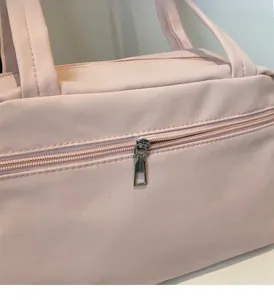 Macro detail of the smooth metal zipper closure on a pink nylon fitness tote bag