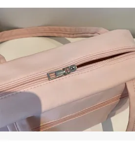 Close-up of smooth silver metal zipper on light pink canvas tote bag detail