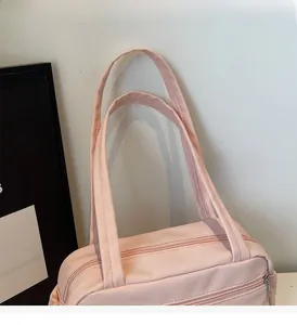 Detail of the pink nylon handbag showing the zipper, front pocket, and soft handle straps