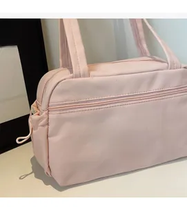 Detail of light pink nylon handbag showing dual handles and front zipper pocket texture