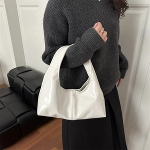 Glossy white hobo bag for women with minimalist seam, worn by model in a stylish setting