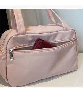 Detail view of pink nylon tote showing front zipper pocket and spacious interior storage