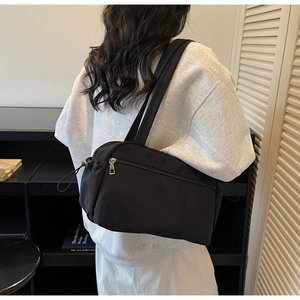 Detailed view of a black nylon tote bag with drawstring side and metal zipper closure