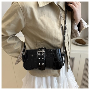 Détail du sac baguette noir aspect crocodile avec grande boucle décorative et clous en métal