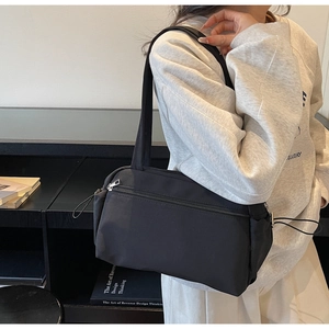 Detail of black nylon tote bag with metal zipper and front pocket in minimalist style