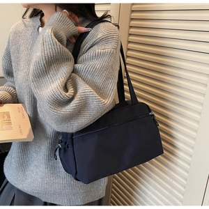 Detailed close-up of dark blue nylon shoulder bag with zipper and drawstring details