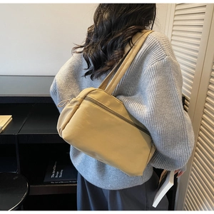 Detail of cream nylon tote bag with drawstring pockets and zipper design on shoulder