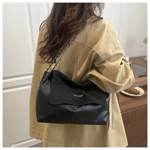 Detailed view of black tote bag featuring mixed leather textures and chain strap