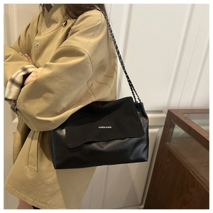 Close-up of black retro tote bag featuring metallic chain strap and printed fashion logo