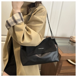 Detail of black leather tote bag with chain strap and Fashion & Bags text on model