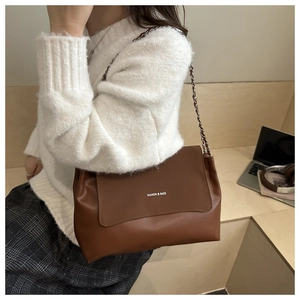 Brown leather tote bag with chain strap shown in a professional office setting