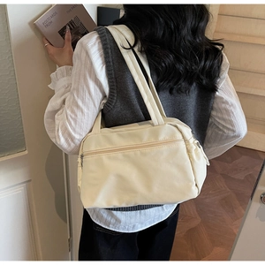 Close-up of cream white nylon tote bag with front zipper pocket on a female shoulder