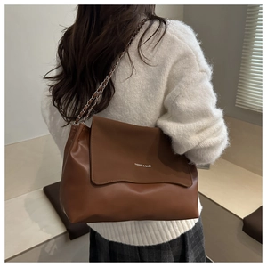 Detail of a brown vintage tote bag with wavy edge design and fashion text printing