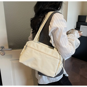 Detail view of a cream minimalist tote bag with zipper pocket worn by a model