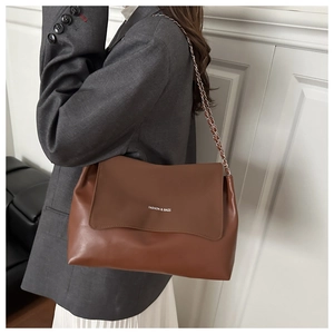 Close-up of a dark brown leather tote bag showing the fashion logo and chain strap