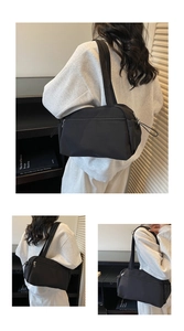Detail view of a black minimalist nylon shoulder bag with drawstring accents and dual straps