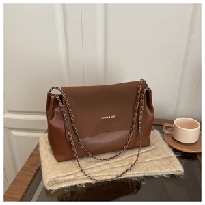 Close-up of caramel leather tote bag with metal chain strap and brand logo detail