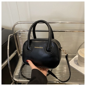 Detail of a black Boston handbag with golden lettering and adjustable shoulder strap