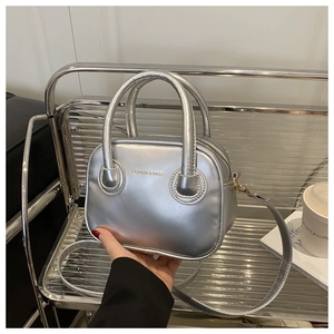 Silver metallic pillow bag with dual round handles and gold Fashion & Bags lettering