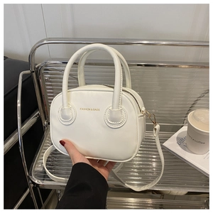 Detailed view of white PU leather round handbag with gold zipper and dual top handles