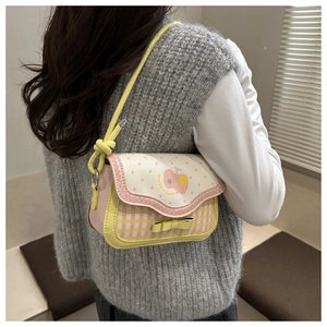 Detail of pink and yellow plaid handbag with cartoon embroidery and bow decoration