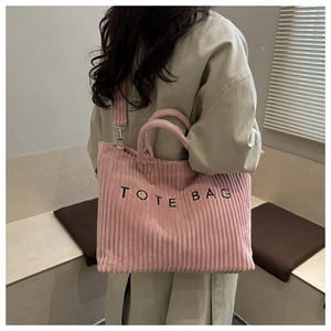 Detailed view of pink corduroy tote bag showing the texture and side-carry style