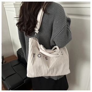 Detailed close-up of white corduroy tote bag with TOTE BAG embroidery and metal hooks