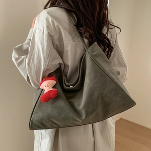 Borsa tote minimalista in camoscio verde scuro con ciondolo a mela su una modella