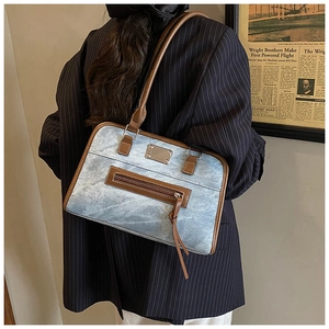 Gros plan du sac fourre-tout en denim rétro avec bordure en cuir marron et plaque